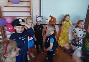 dzieci w przebraniach karnawałowych tańczą na balu przebierańców, na sali gimnastycznej
