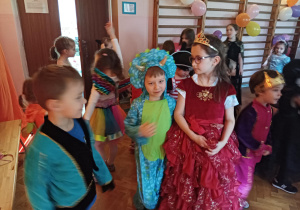 dzieci w przebraniach karnawałowych tańczą na balu przebierańców, na sali gimnastycznej