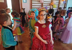 dzieci w przebraniach karnawałowych tańczą na balu przebierańców, na sali gimnastycznej