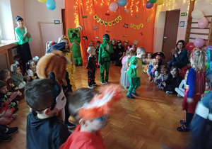 dzieci w przebraniach karnawałowych tańczą na balu przebierańców, na sali gimnastycznej