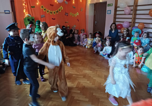 dzieci w przebraniach karnawałowych tańczą na balu przebierańców, na sali gimnastycznej