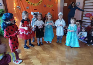 dzieci w przebraniach karnawałowych tańczą na balu przebierańców, na sali gimnastycznej