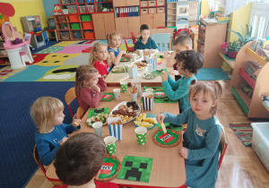 dzieci przy stolikach świętują wspólnie urodziny kolegi