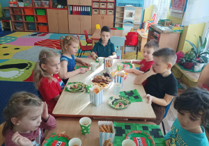 dzieci przy stolikach świętują wspólnie urodziny kolegi