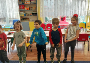 dzieci stoją w sali, w tle duże okna