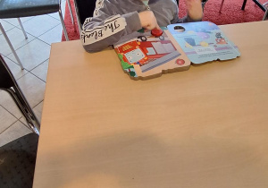 chłopiec ogląda książki przy stoliku w bibliotece