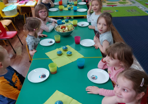 Dzieci siedzą przy stole i zjadają tort.