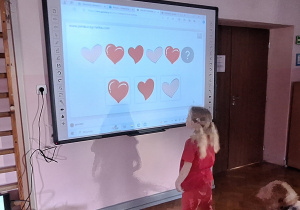 Dziewczynka rozwiązuje zadanie na tablicy interaktywnej.