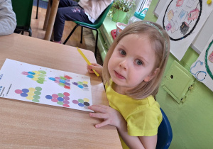 Dzieci siedzą przy stoliku i wykonują zadanie z kodowania.