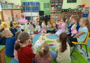 Dzieci siedzą w kole i trzymają pacynki.