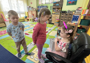 Dzieci podchodzą do dziewczynki na krześle i składają jej życzenia.