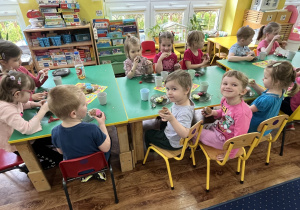 Dzieci siedzą przy stole i zjadają słodycze.