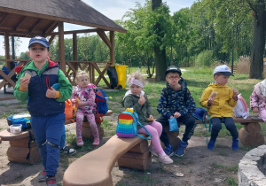 dzieci siedzą na ławeczkach, spożywają posiłek