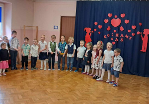 Dzieci w półkolu recytują wiersz przed rodzicami.