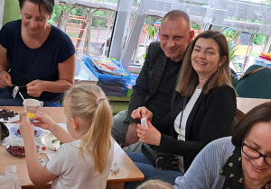Dzieci wraz z rodzicami siedzą przy stolikach.