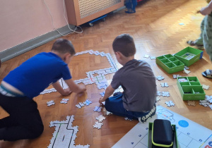 Dzieci na podłodze układają drogę z puzzli dla ozobota.