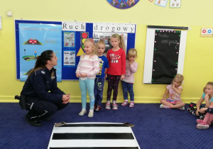 Dzieci z grupy 3 i 4 uczą się przechodzić przez pasy pod okiem policjantek.