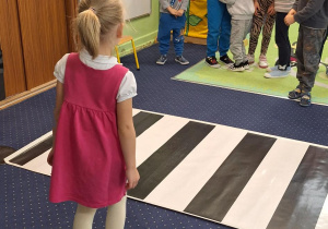 Na podłodze rozłożone przejście dla pieszych, Dzieci stoją dookoła.