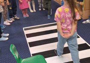 Na podłodze rozłożone przejście dla pieszych, Dzieci stoją dookoła.