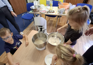 dzieci przy stolikach robią ciasto na babeczki
