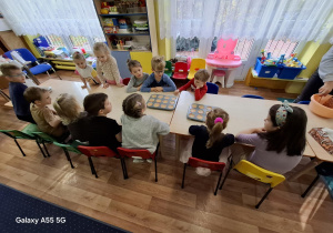 dzieci przy stolikach robią ciasto na babeczki