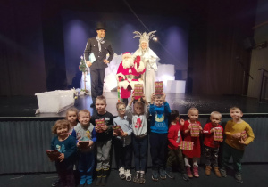 Grupa dzieci w teatrze pozuje do zdjęcia z Mikołajem