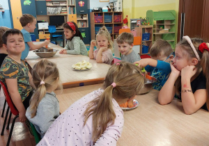 dzieci przy stolikach wykonują surówkę z marchewki