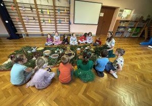 Dzieci siedzą i słuchają panią.