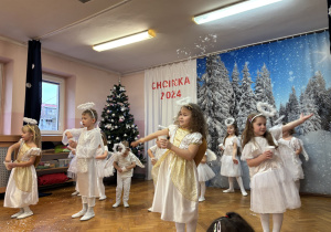Dzieci na scenie rozsypują śnieg przy piosence.