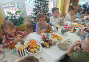 dzieci przy stolikach degustują słodycze, owoce, piją soki
