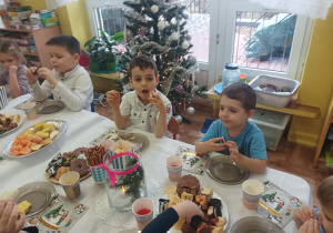 dzieci przy stolikach degustują słodycze, owoce, piją soki