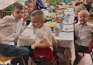 Dzieci siedzą przy wigilijnym stole.