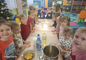 dzieci stoją przy stolikach, na stolikach widać produkty do przygotowania gofrów, jajka, mleko, olej, garnek