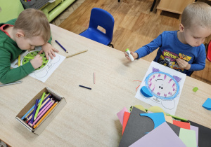 Dzieci wykonują pracę plastyczną przy stolikach.
