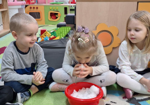 Dzieci siedzą na dywanie i oglądają śnieg.