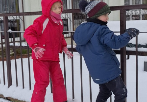 Dzieci bawią się na śniegu w przedszkolnym ogrodzie.