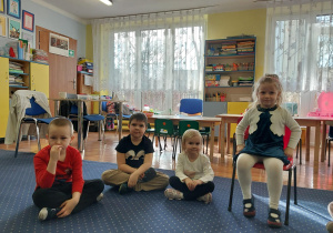 dziewczynka świętuje urodziny, siedzi na krzesełku, dookoła niej dzieci składają jej życzenia