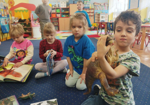 dzieci oglądają albumy o dinozaurach