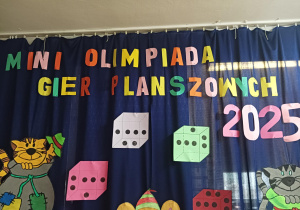duży kolorowy napis "Mini olimpiada gier planszowych GRANNA" umieszczony na granatowym materiale