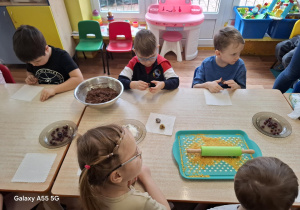 dzieci przy stolikach samodzielnie wykonują słodycze z płatków owsianych, bananów, kakao