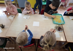 dzieci przy stolikach samodzielnie wykonują słodycze z płatków owsianych, bananów, kakao