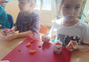 dzieci podczas zajęć kulinarnych przygotowują deser w małym słoiczku, kroją owoce, nakładają jogurt do słoiczków