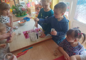dzieci podczas zajęć kulinarnych przygotowują deser w małym słoiczku, kroją owoce, nakładają jogurt do słoiczków