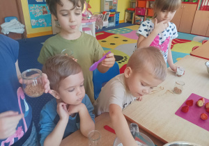 dzieci podczas zajęć kulinarnych przygotowują deser w małym słoiczku, kroją owoce, nakładają jogurt do słoiczków