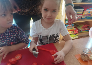dzieci podczas zajęć kulinarnych przygotowują deser w małym słoiczku, kroją owoce, nakładają jogurt do słoiczków