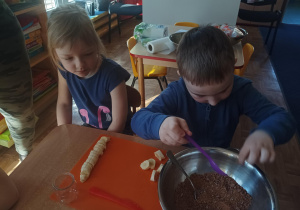 dzieci podczas zajęć kulinarnych przygotowują deser w małym słoiczku, kroją owoce, nakładają jogurt do słoiczków