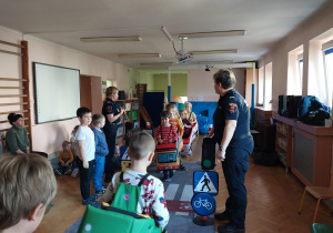 dzieci uczestniczą w zajęciach o bezpieczeństwie na sali gimnastycznej, poruszają się po drodze i po pasach zgodnie z przepisami ruchu drogowego