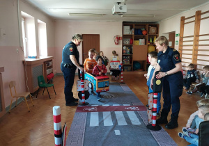 dzieci uczestniczą w zajęciach o bezpieczeństwie na sali gimnastycznej, poruszają się po drodze i po pasach zgodnie z przepisami ruchu drogowego
