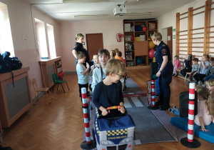 dzieci uczestniczą w zajęciach o bezpieczeństwie na sali gimnastycznej, poruszają się po drodze i po pasach zgodnie z przepisami ruchu drogowego