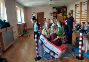 dzieci uczestniczą w zajęciach o bezpieczeństwie na sali gimnastycznej, poruszają się po drodze i po pasach zgodnie z przepisami ruchu drogowego